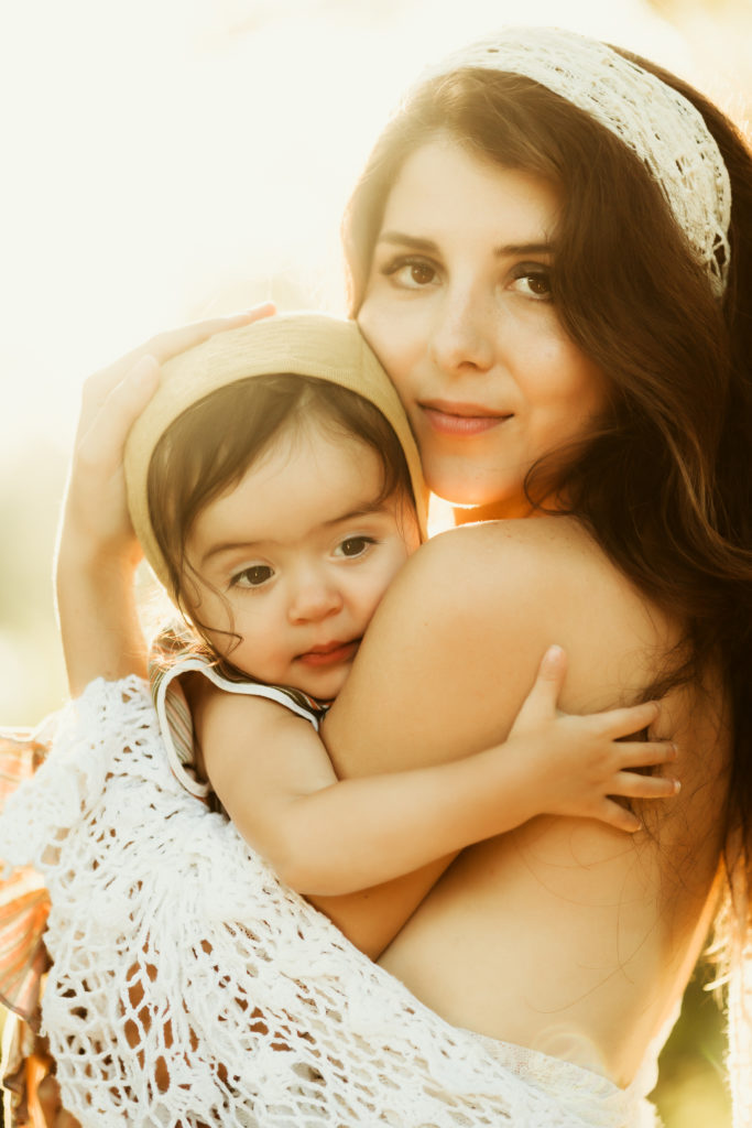 dreamy vintage ethereal boho breastfeeding portraits of a mother and young child standing with the sun shining behind them at Edward medard park 