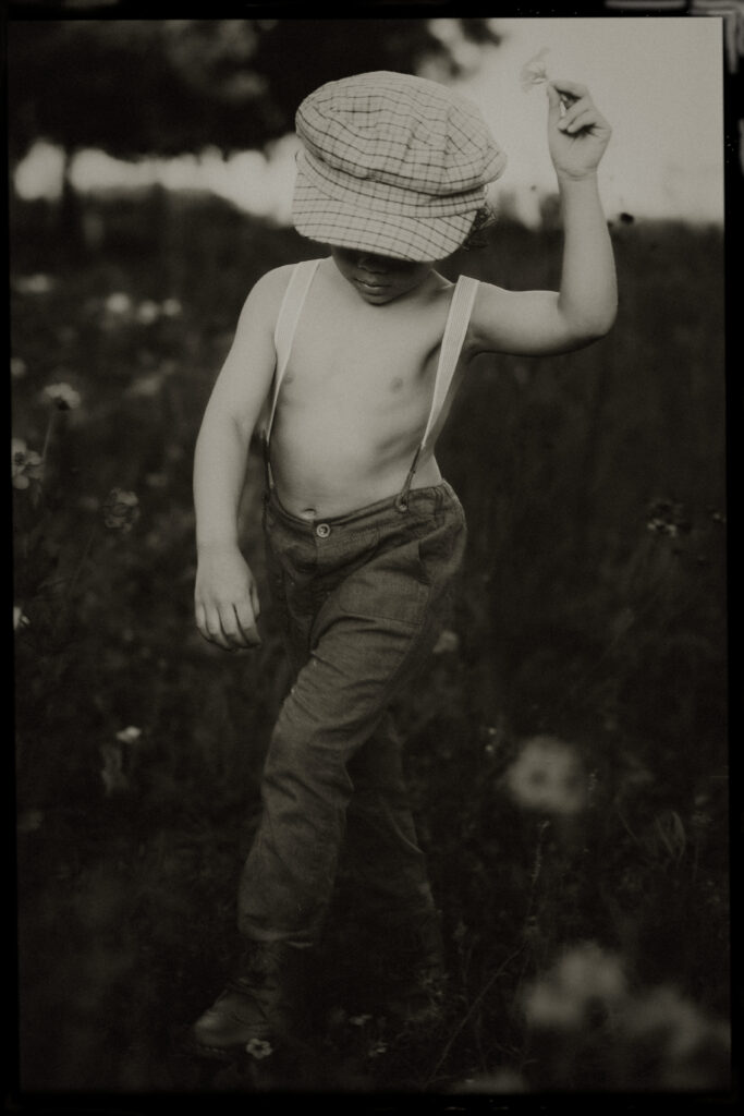 50's inspired childhood portraits with a toddler wearing overalls running in a flower field 